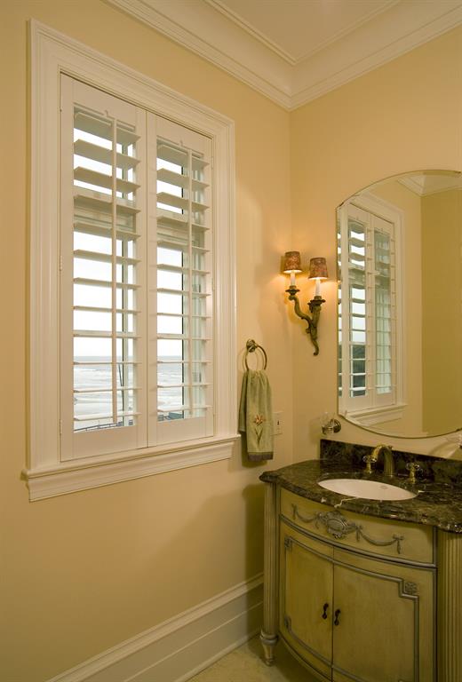 White shutters in a light bathroom outlooking the ocean